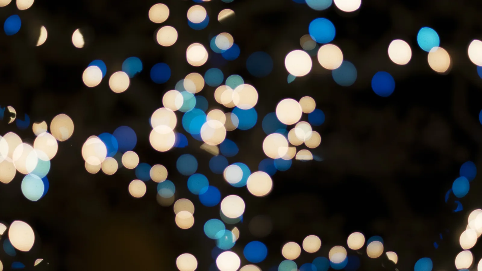 Out-of-focus Christmas lights glowing gold and white.