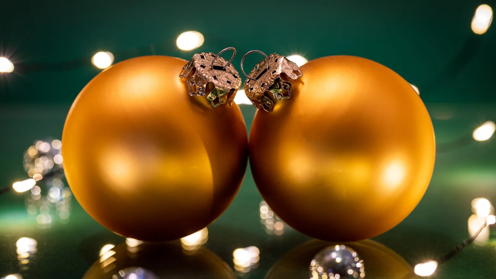 Red and gold glass Christmas ornaments hanging close together.
